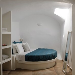 Ein kleines Schlafzimmer mit einem gewölbten Bett, einem Einbauschrank und einem großen Spiegel.