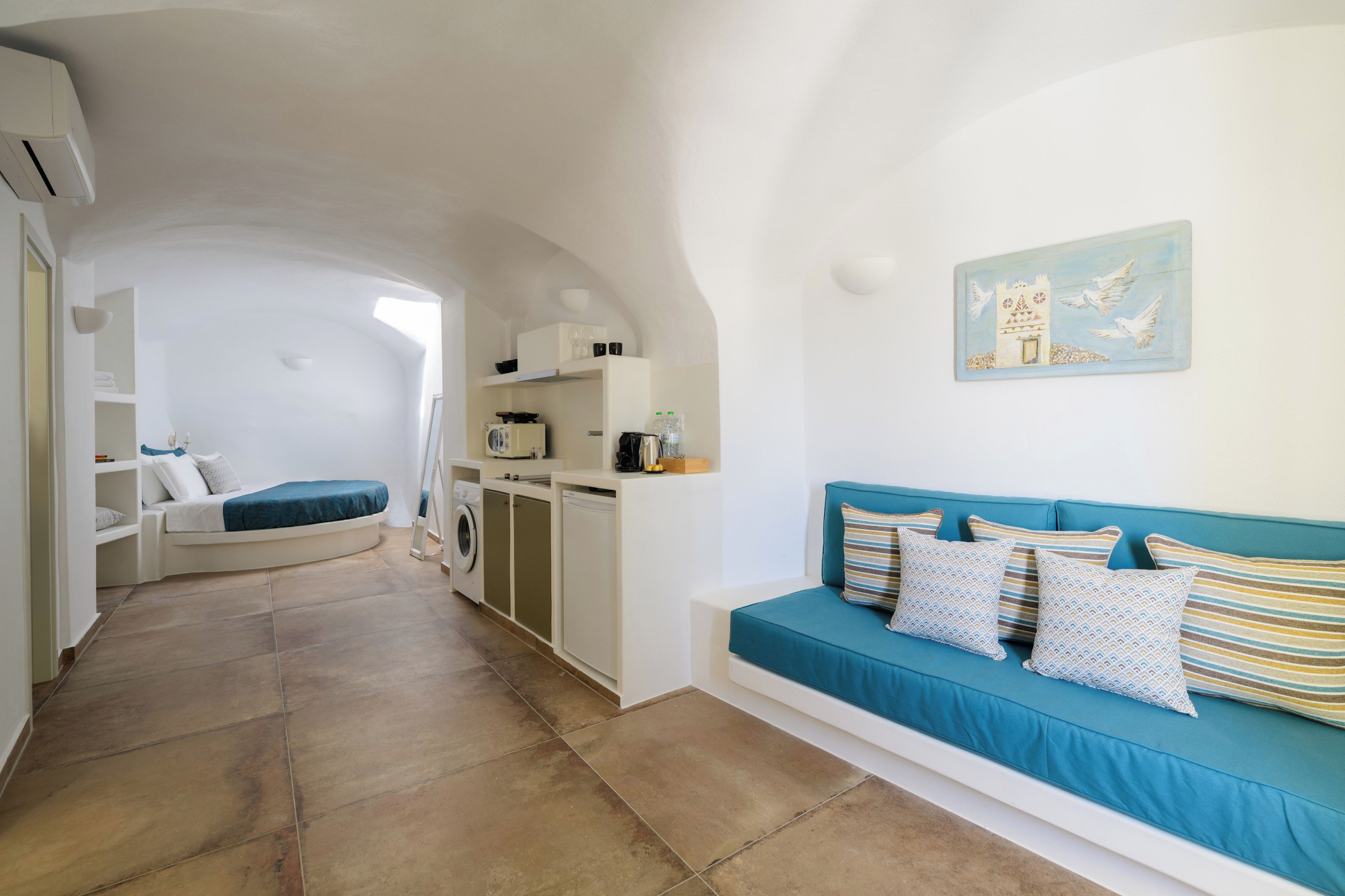 A compact living space with a kitchenette, a sofa, and a bed.