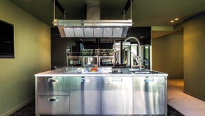 Een moderne keuken met een centraal eiland, roestvrijstalen apparatuur en een groot raam.