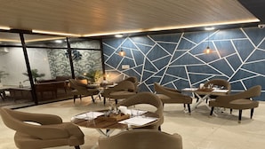 A modern interior with a geometric wall design, round tables, and comfortable seating. - Hotel Raaso Inn (Jaipur)