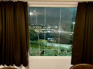 Janela com vista para um horizonte urbano noturno, incluindo edifícios e uma estrada.