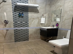 Ein Badezimmer mit Dusche, Toilette, Waschbecken und Spiegel.