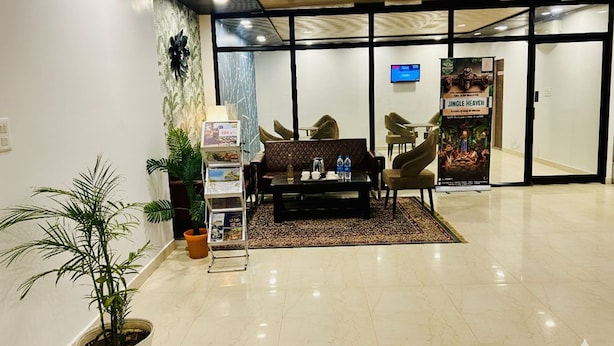 A lobby with a reception desk, seating area, and a poster. - Hotel Raaso Inn (Jaipur)