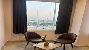 A room with two chairs, a small table, and a window with curtains. - Hotel Raaso Inn (Jaipur)