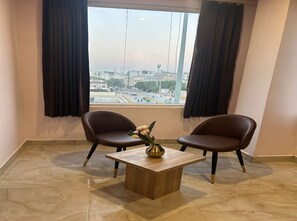 A room with two chairs, a small table, and a window with curtains. - Hotel Raaso Inn (Jaipur)