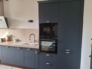 Een moderne keuken met een dubbele spoelbak, een magnetron en een inbouwoven.