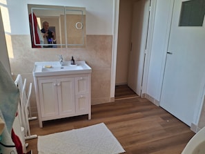 Ein Badezimmer mit einem weißen Waschbecken, einem Spiegel und Holzboden.