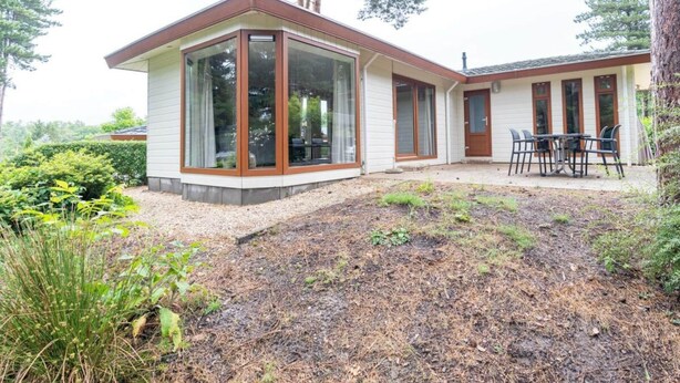 A modern house with large windows, a patio with a table and chairs, and a well-maintained garden. - Holiday Home in Brunssum With Terrace (Brunssum)