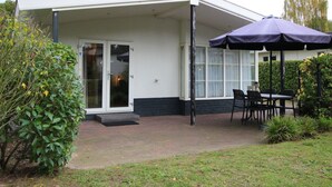 A modern house with a covered patio, a glass door, and a table with chairs. - Holiday Home in Brunssum With Terrace (Brunssum)