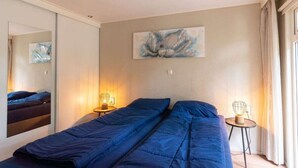 A bedroom with a bed, two bedside tables, a mirror, and a painting on the wall. - Holiday Home in Brunssum With Terrace (Brunssum)