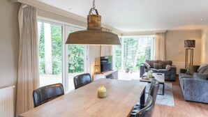 A spacious living area with a dining table, sofas, and a TV. - Holiday Home in Brunssum With Terrace (Brunssum)