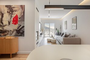 A modern living room with a sofa, ottomans, a coffee table, and a large abstract painting on the wall. - Spefsippou37·Kolonaki Skyline Views (Athens)