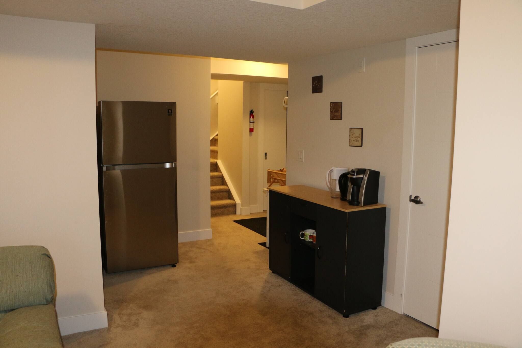 Cocina compacta con refrigerador, cafetera y un mueble con una taza.