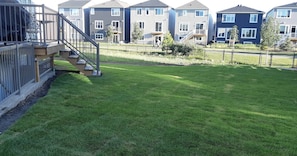 A residential area with a well-maintained lawn, a wooden deck, and a staircase leading to a balcony. - Lovely Guest Suite in Calgary (Calgary)