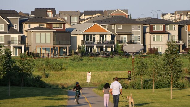 A residential area with houses, a paved path, and a grassy field.