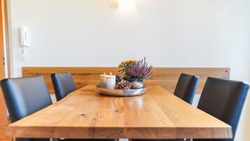 Ein Holztisch mit sechs schwarzen Stühlen, eine kleine Blumenkomposition und zwei Kerzen.