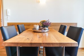 A wooden dining table with six black chairs, a small floral arrangement, and two candles. - Simon's Vacation Rental 5 - Your Retreat with a Panoramic View (Kurort Oberwiesenthal)