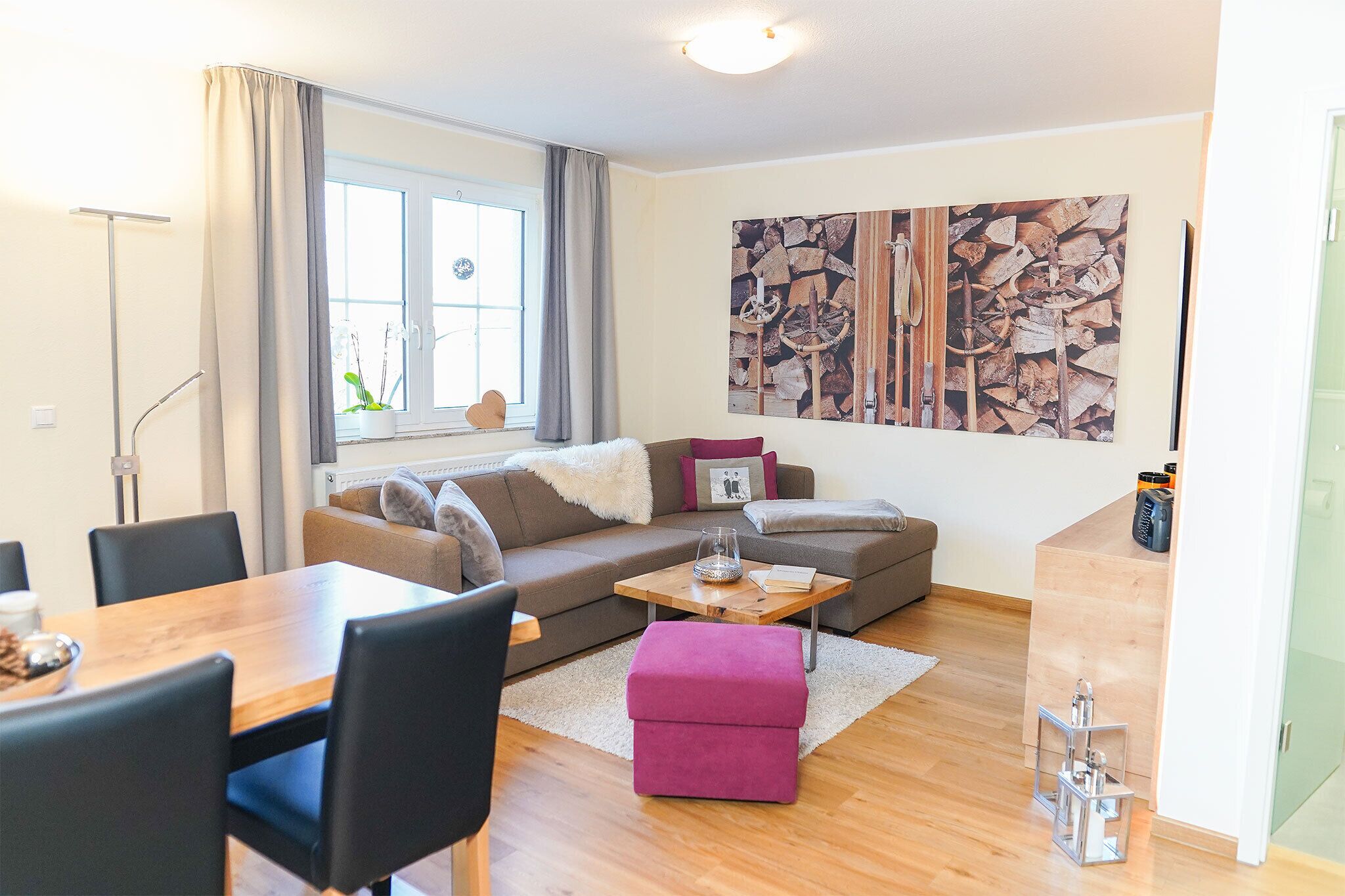 Ein modernes Wohnzimmer mit Sofa, Hocker, Couchtisch und Essbereich.