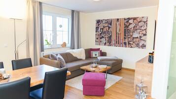 Ein modernes Wohnzimmer mit Sofa, Hocker, Couchtisch und Essbereich.