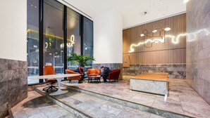 A modern lobby with a reception desk, seating area, and large windows. - SKY HIGH Apartment (Melbourne)