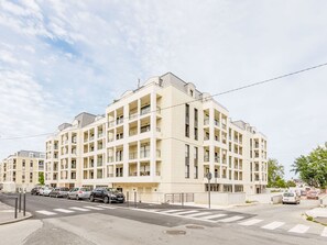 A multi-story residential building with balconies, a crosswalk, and parked cars. - Newquay by Interhome (Dinard)