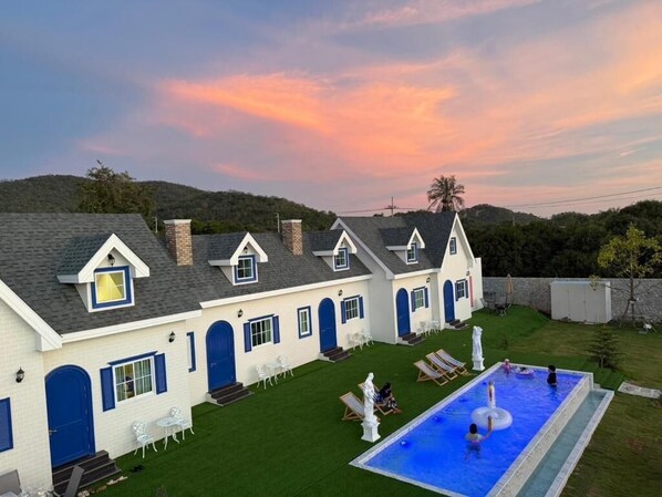 A house with a swimming pool, white exterior, and blue accents.
