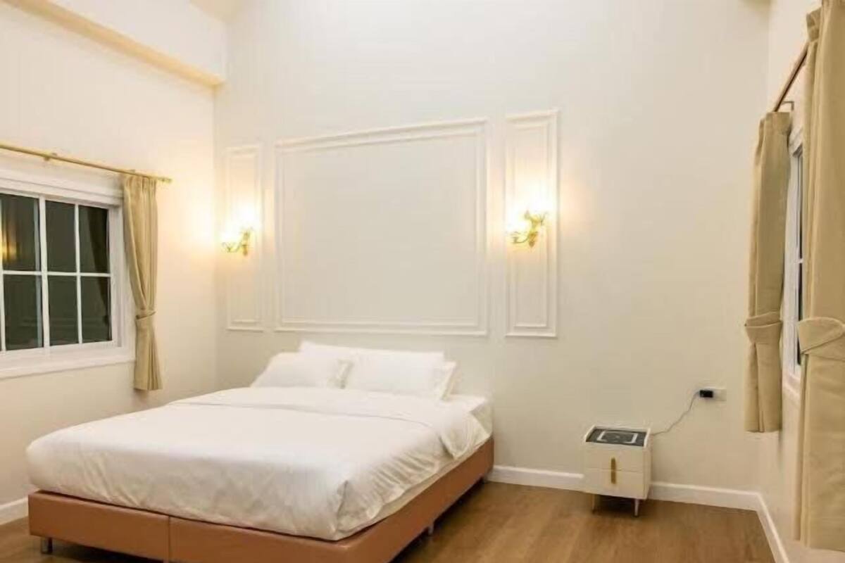 Un dormitorio con cama, mesita de noche, luz empotrada en la pared y toma de corriente.