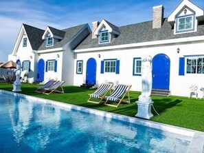 A large house with a swimming pool, multiple blue doors, and a statue. - British Hill Resort (Sattahip)