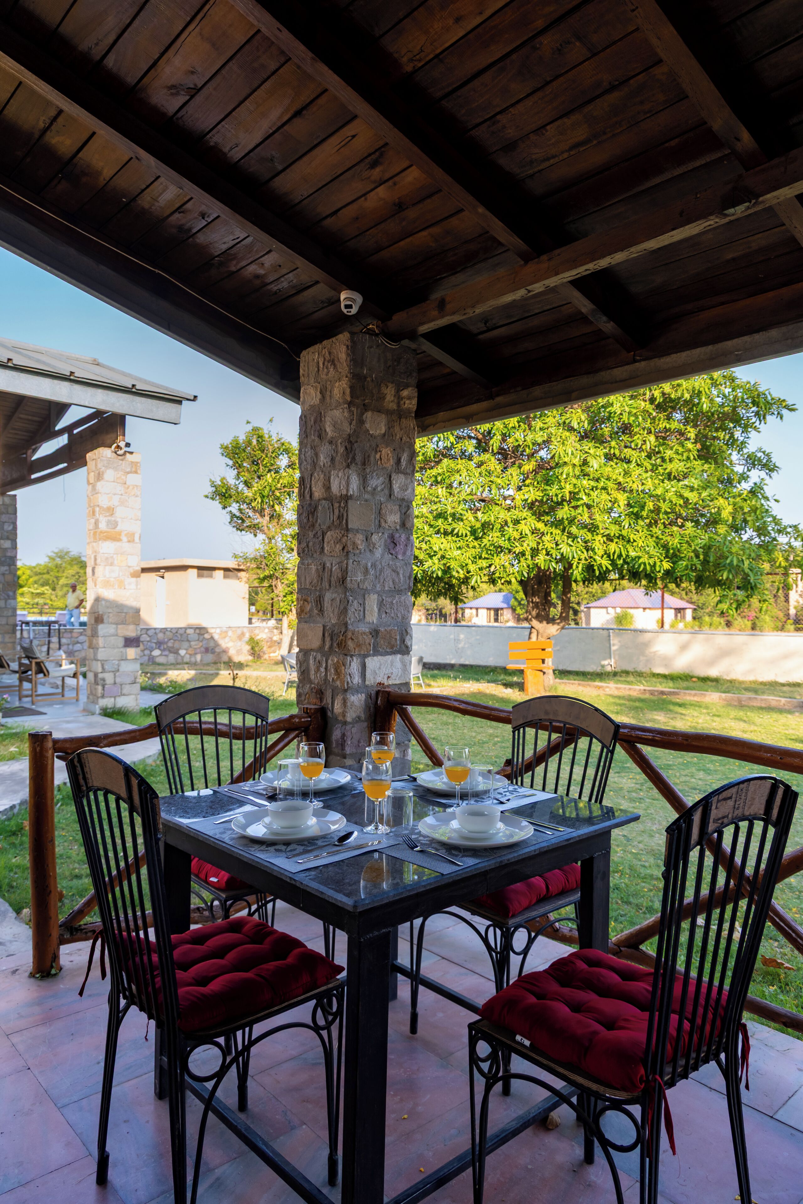 A covered patio with a table set for four, stone pillar, and outdoor seating.