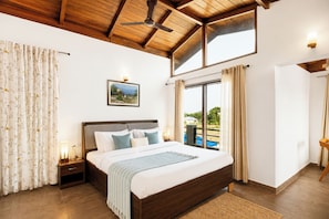 A bedroom with a large bed, wooden ceiling, a nightstand, a lamp, a painting, and a view of a pool. - Alaya Stays Dhela Jungle Retreat (Dhela)