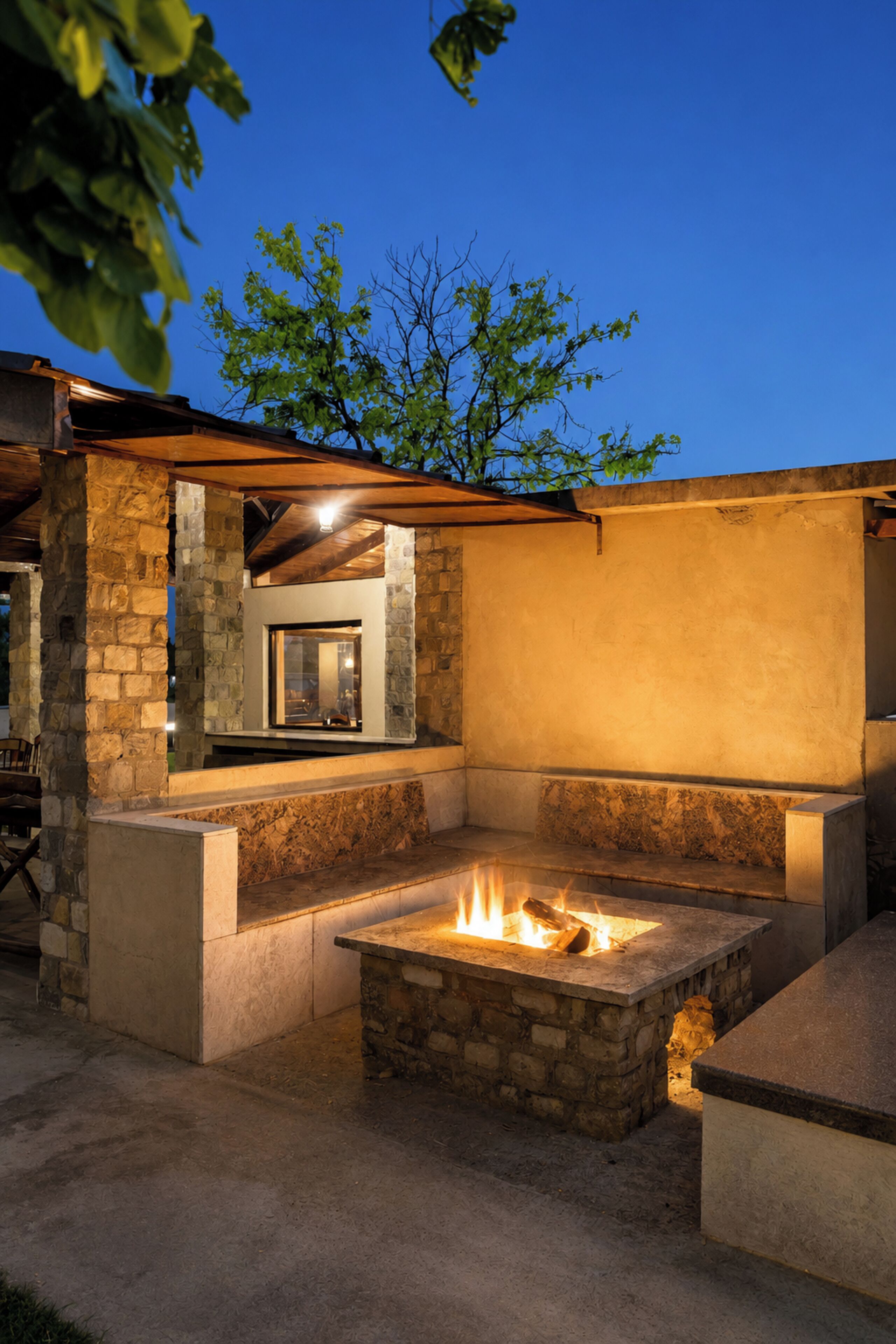 An outdoor patio with a stone fire pit, a built-in seating area, and a view of the sky.