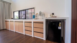 A modern kitchen with a built-in refrigerator, a sink, and a window with blinds.