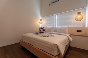 Ein modernes Schlafzimmer mit einem Holzbettgestell, weißer Bettwäsche und zwei hängenden Pendelleuchten.