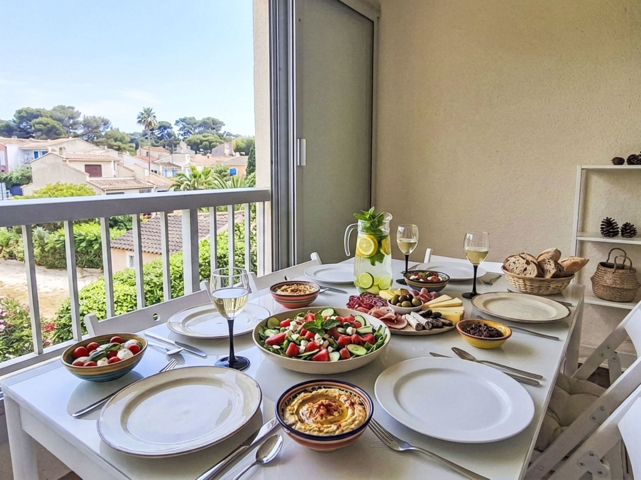 A balcony dining setup with a table set for four, including plates, cutlery, and various dishes.