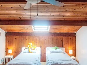 A room with wooden panel walls, a ceiling fan, two beds with pillows, and bedside lamps. - Le Clos des Pecheurs by Interhome (Six Fours)