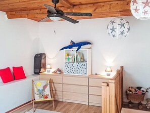 A child's room with a ceiling fan, a bookshelf, a small desk, a red pillow, a rabbit painting, and a starfish wall decoration. - Le Clos des Pecheurs by Interhome (Six Fours)