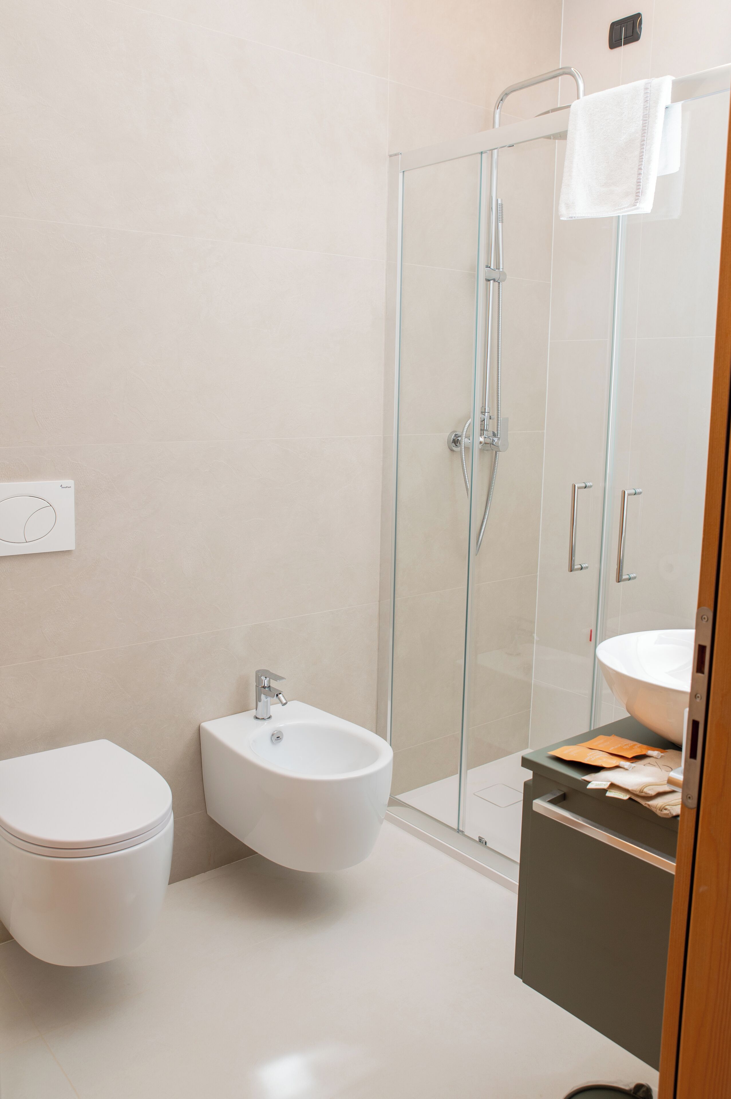 A modern bathroom with a glass-enclosed shower, a white toilet, and a bidet.