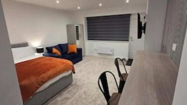A modern bedroom with a bed, a desk, and a chair. - The Snug by JS Apartments (Blackburn)