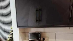 A compact kitchen with a microwave, a small oven, and a washing machine. - The Snug by JS Apartments (Blackburn)