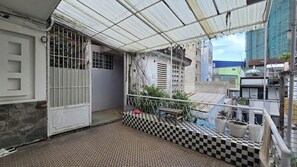 Ein Balkon mit kariertem Boden, einem Metallgitter und Blumentöpfen.