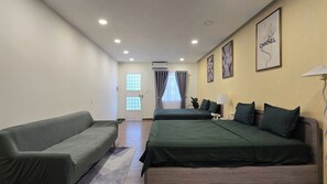 Quarto de hotel com duas camas, um sofá, uma luminária e obras de arte nas paredes.