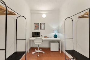 A compact room with a white desk, a chair, a small white cabinet, and two wall-mounted shelves with clothing. - [Vernazza Prestige] 5TERRE/ 10 mt the sea+A/C (Vernazza)