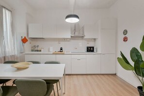 A modern kitchen with white cabinets, a dining table with chairs, a hanging light fixture, and a potted plant. - [Vernazza Prestige] 5TERRE/ 10 mt the sea+A/C (Vernazza)