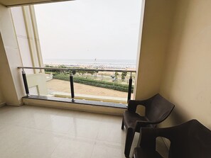 Ein Balkon mit Blick auf einen Strand, ein Stuhl und ein Geländer.