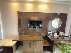 A modern bathroom with a wooden vanity, a built-in TV, a mirror, and a glass partition. - Puri Golden Palace Near Sea Beach (Puri)