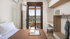 Una camera da letto con un letto, una scrivania, una sedia, un armadio e un balcone con tavolo e sedie.