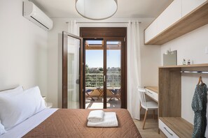 Ein Schlafzimmer mit Bett, Schreibtisch, Stuhl, Kleiderschrank und einem Balkon mit Tisch und Stühlen.