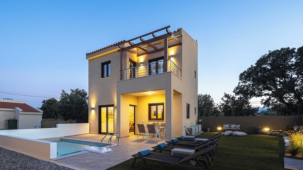 Una moderna casa a due piani con piscina, area salotto esterna e un patio ben illuminato.