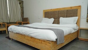 Ein hölzernes Bett mit weißer Bettwäsche, einer grauen Tagesdecke und einem Kopfteil mit einer gepolsterten Lehne.