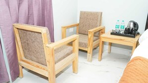 Ein Zimmer mit zwei Holzstühlen, einem kleinen Holztisch, einem Bett und einem Vorhang.